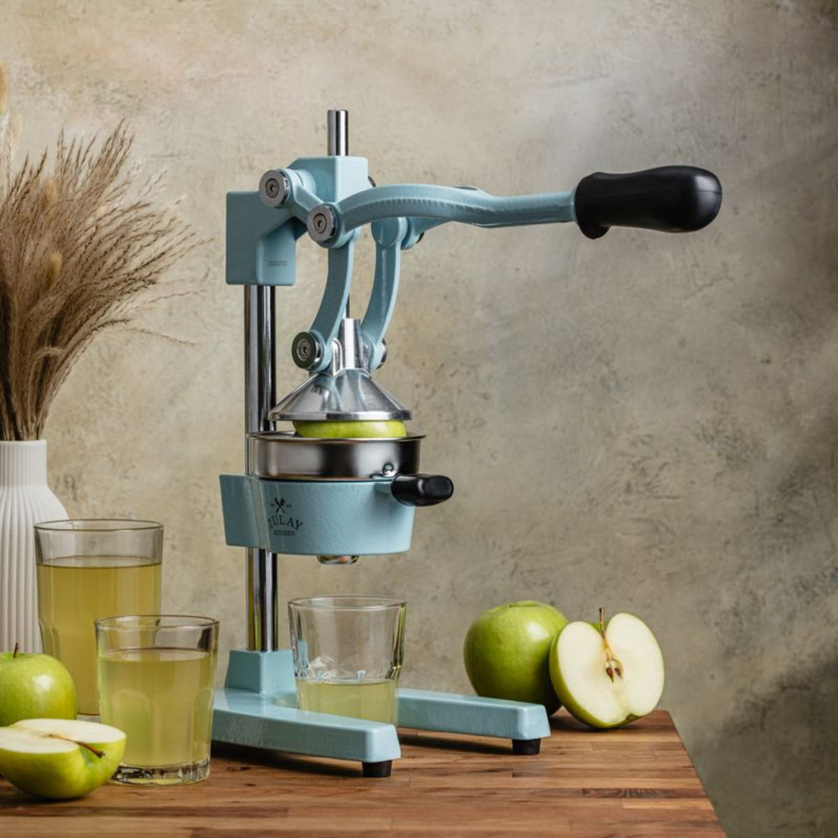 BlueKitchen Manual juicer with apples and juice on a wooden table
