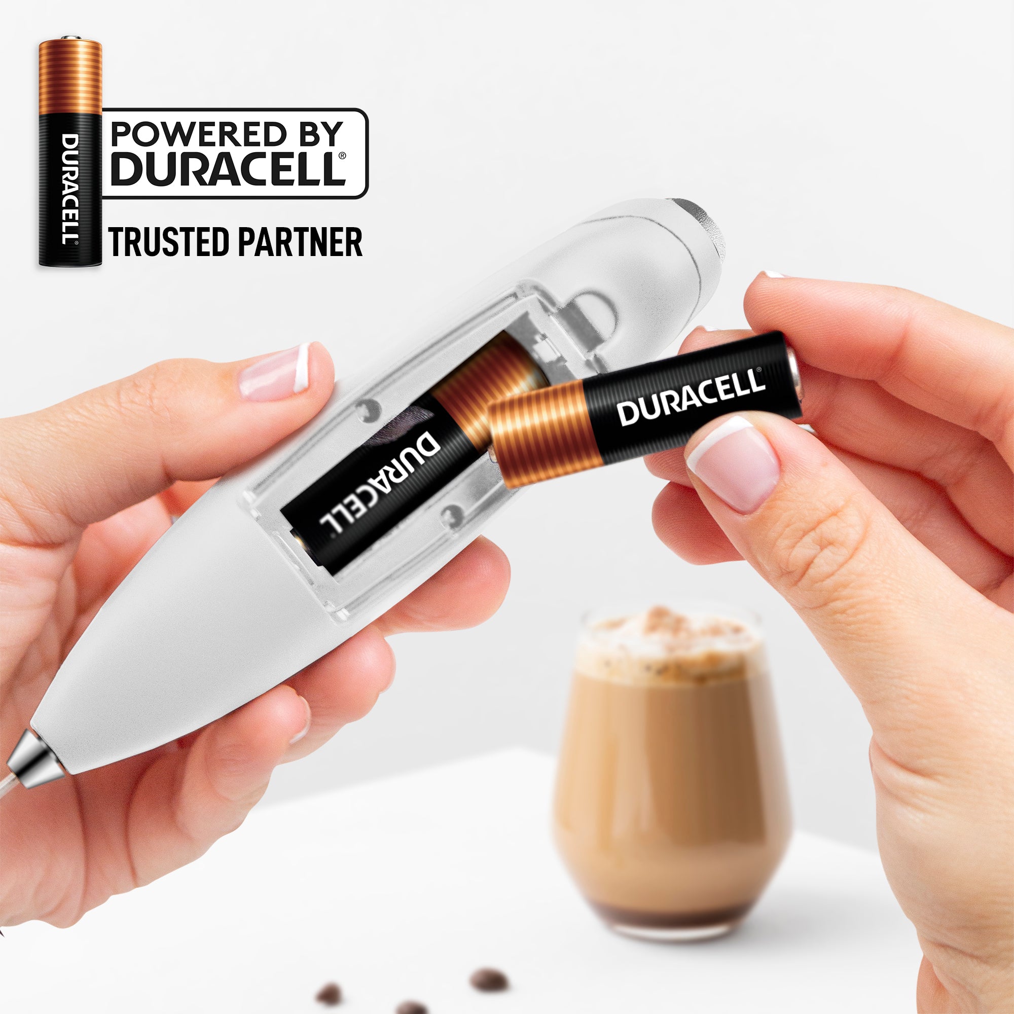 Person holding a device with Duracell batteries, coffee in the background