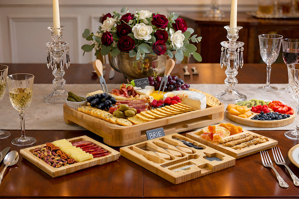 Bamboo Cheese Board Set with various foods on a dining table with wine glasses and candles.