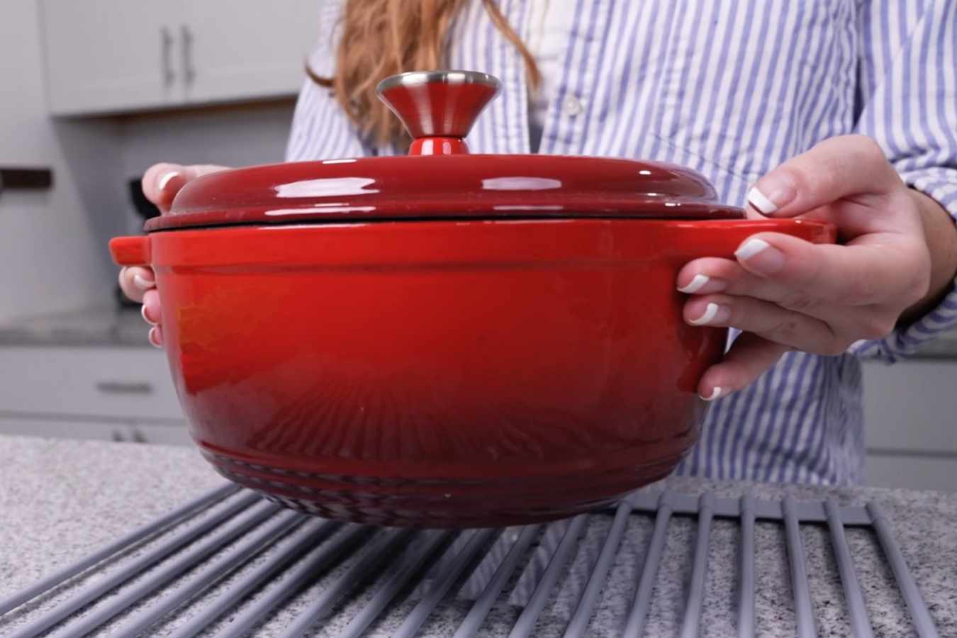 A woman lifting the Zulay Kitchen Dutch oven properly into a rack.