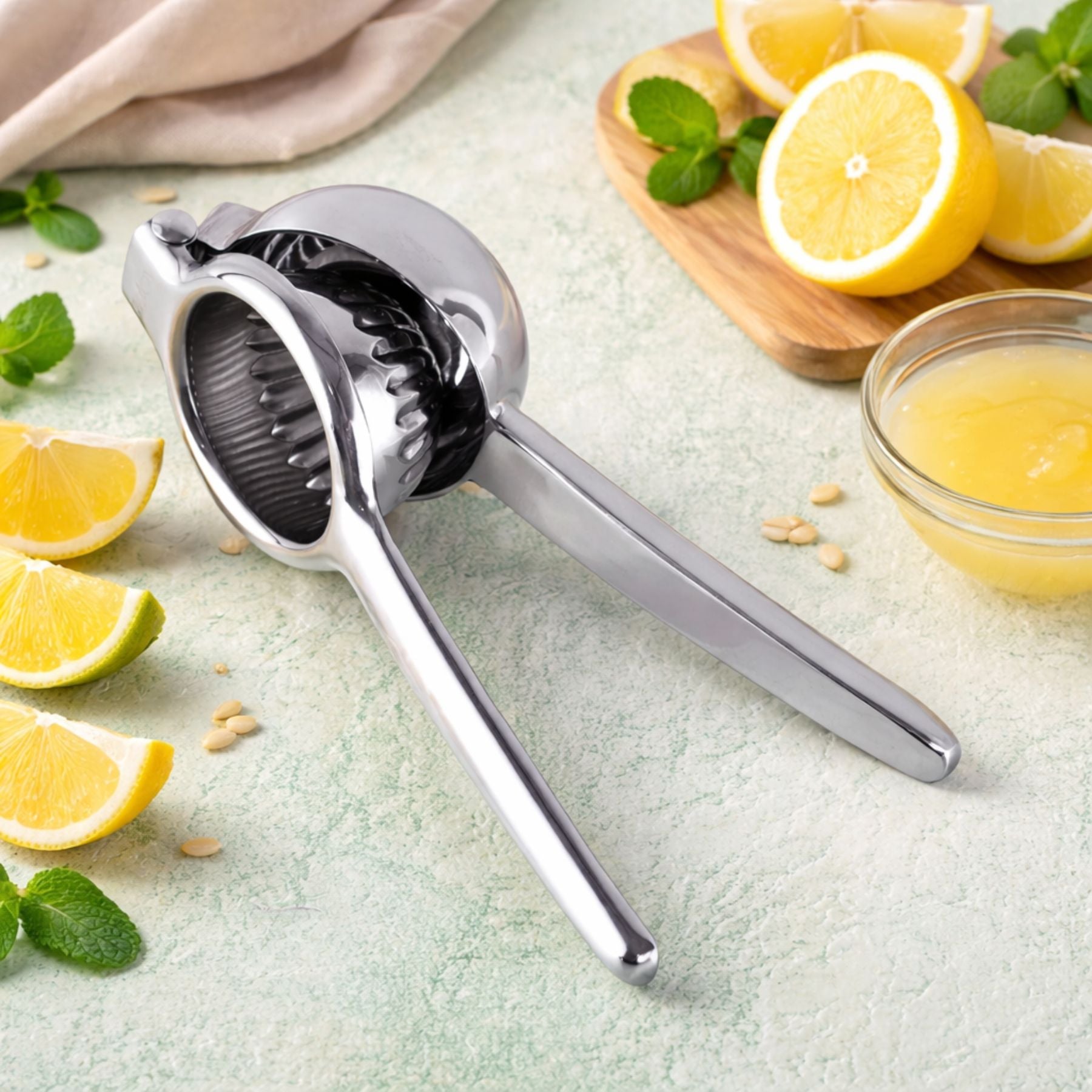 Zulay Kitchen Stainless Steel Lemon Squeezer on a light surface with lemons and a bowl of juice in the background.