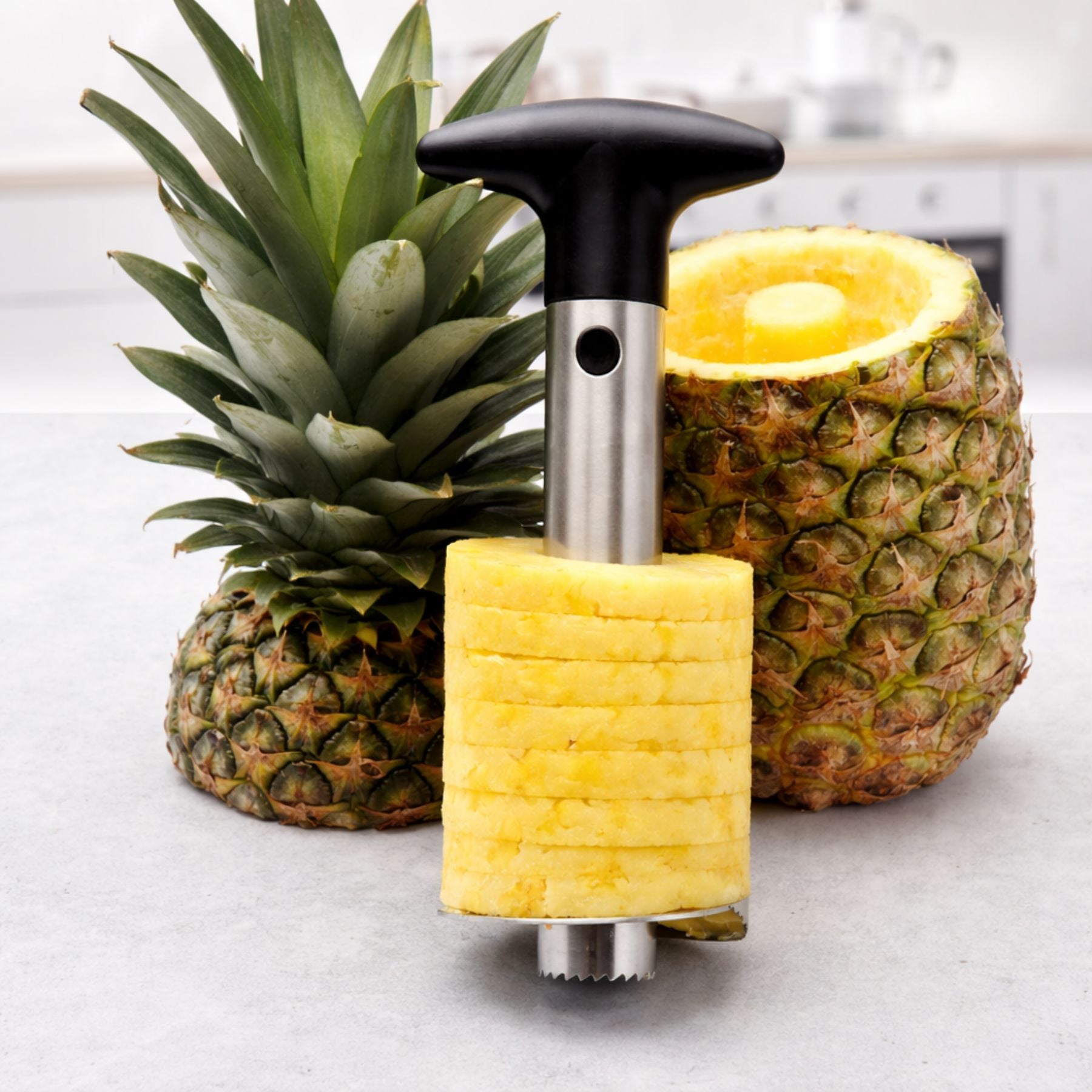 Pineapple slicer cutting a pineapple on a white surface
