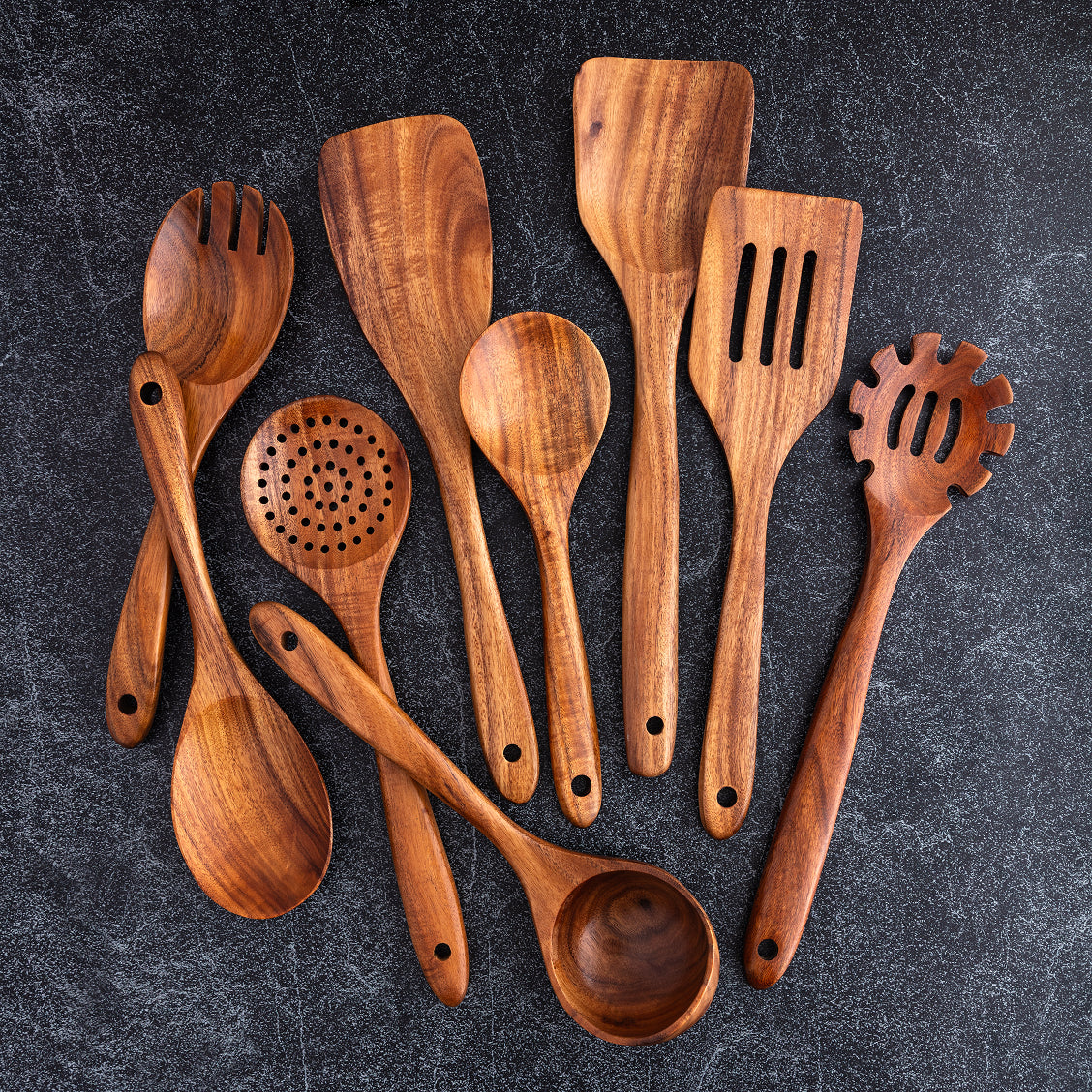 Set of wooden kitchen utensils on a dark surface