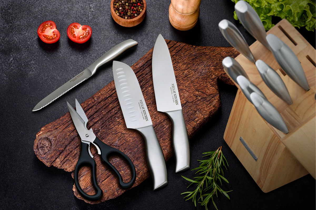 Set of knives on a wooden cutting board with vegetables and a knife block.
