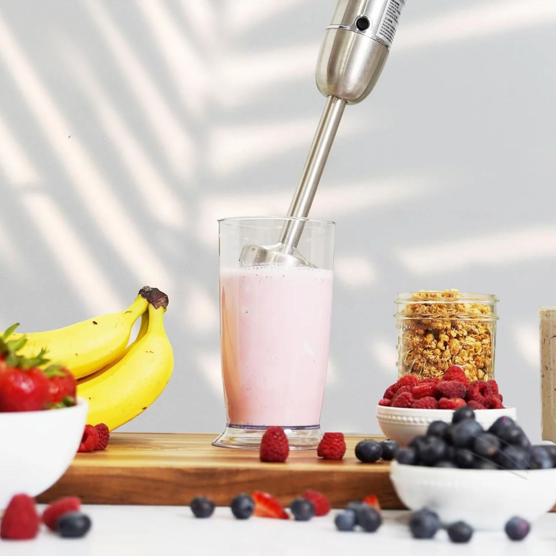 Zulay Kitchen 3-in-1 Immersion Blender mixing a smoothie with fruits and granola on a table.