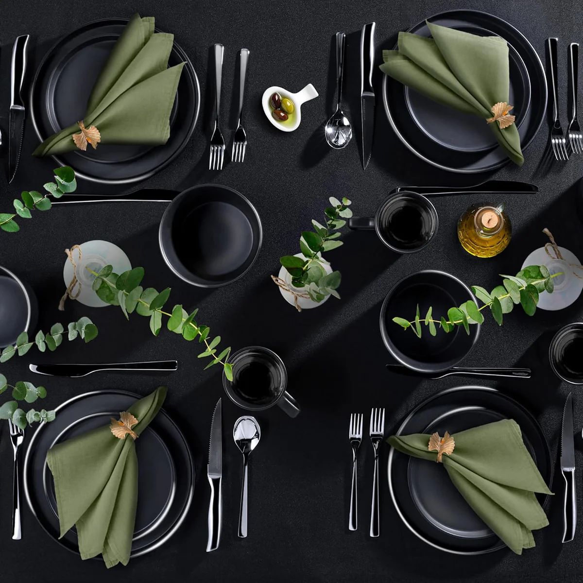 Elegant black and green table setting with plates, napkins, and cutlery on a dark surface.