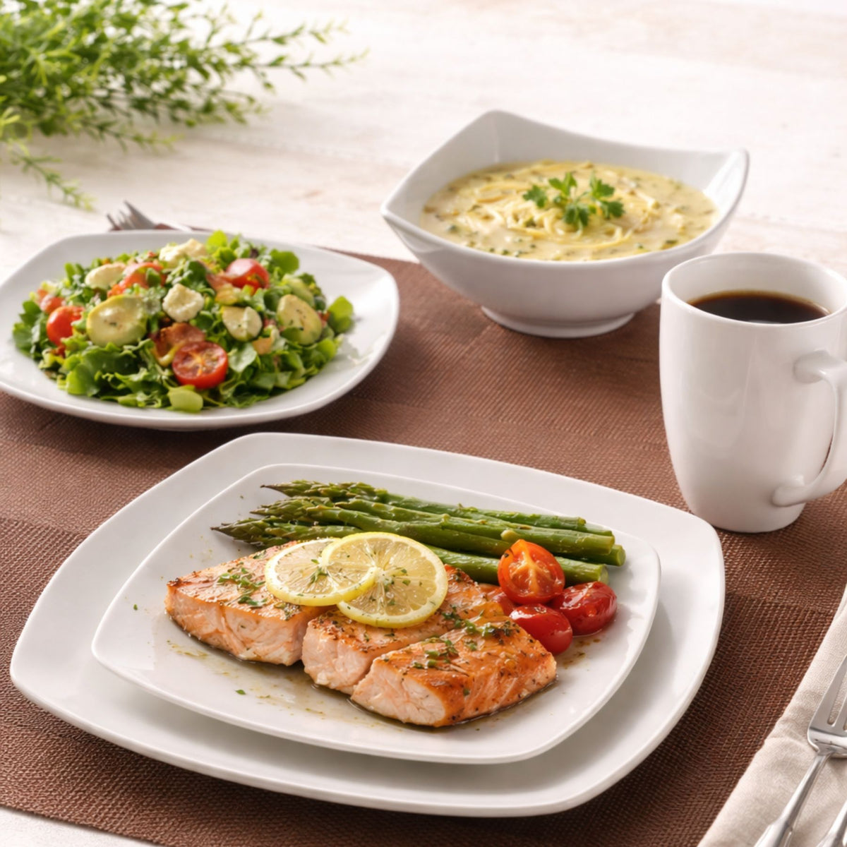 Dinner setting with salmon, asparagus, tomatoes, salad, and a cup of coffee on a table.
