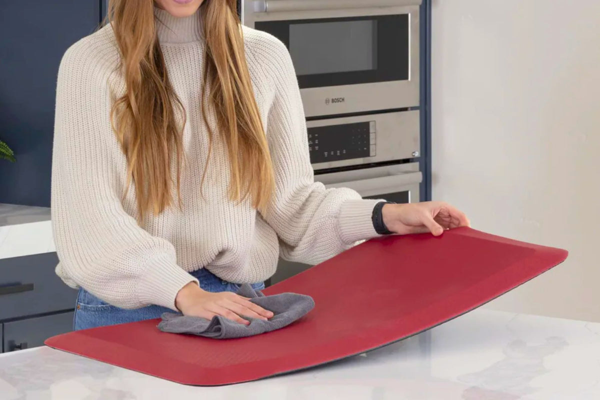 Person using a red mat with a gray cloth on a kitchen counter