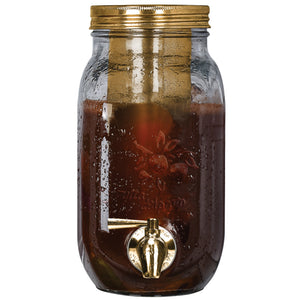 Glass jar with gold lid and spigot filled with a dark liquid on a white background