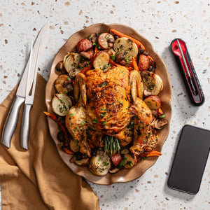 Roasted Chicken on a plate, cellphone & the Grill Tech thermometer on a kitchen counter. 