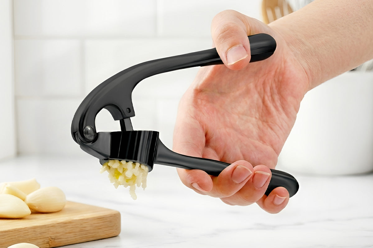 Person using the Zuki Garlic Press Set to crush garlic with a white background