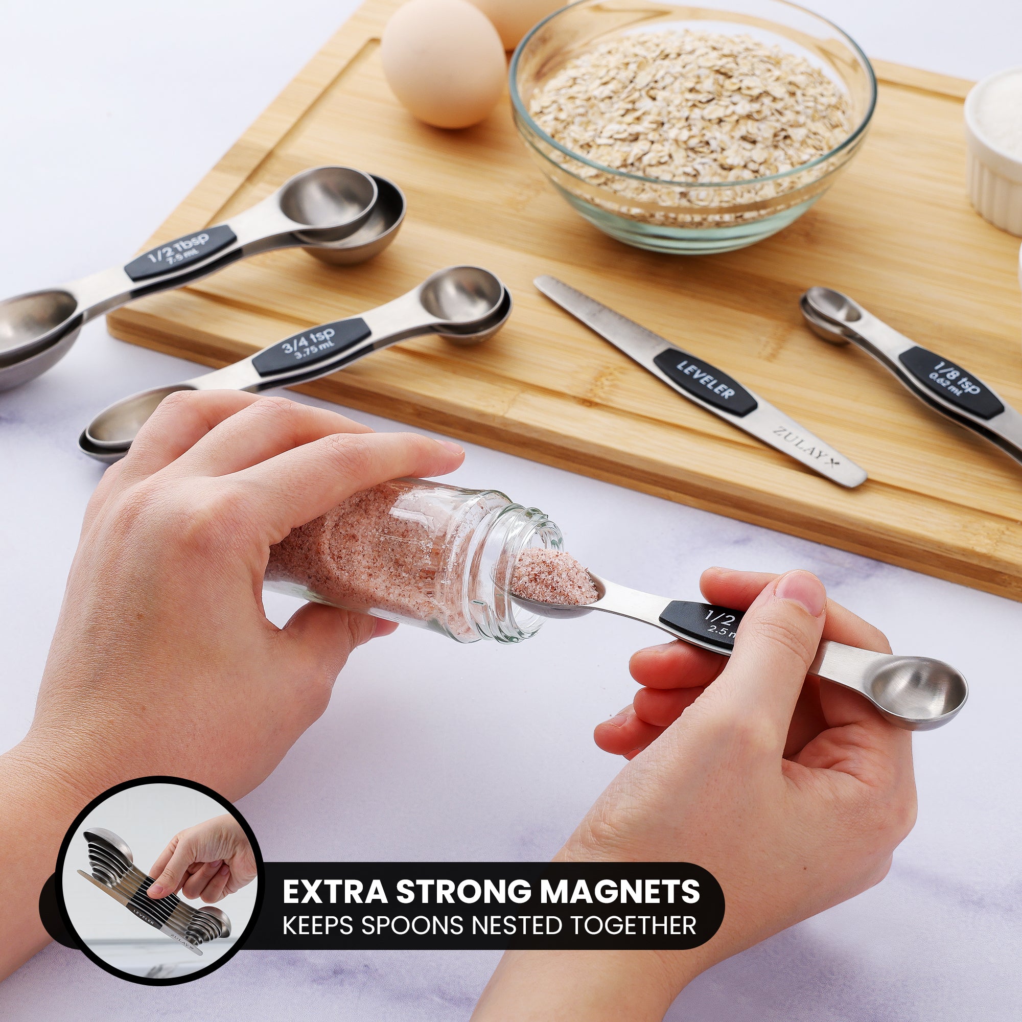 Person using a measuring spoon with magnetic property, surrounded by kitchen items on a wooden board.