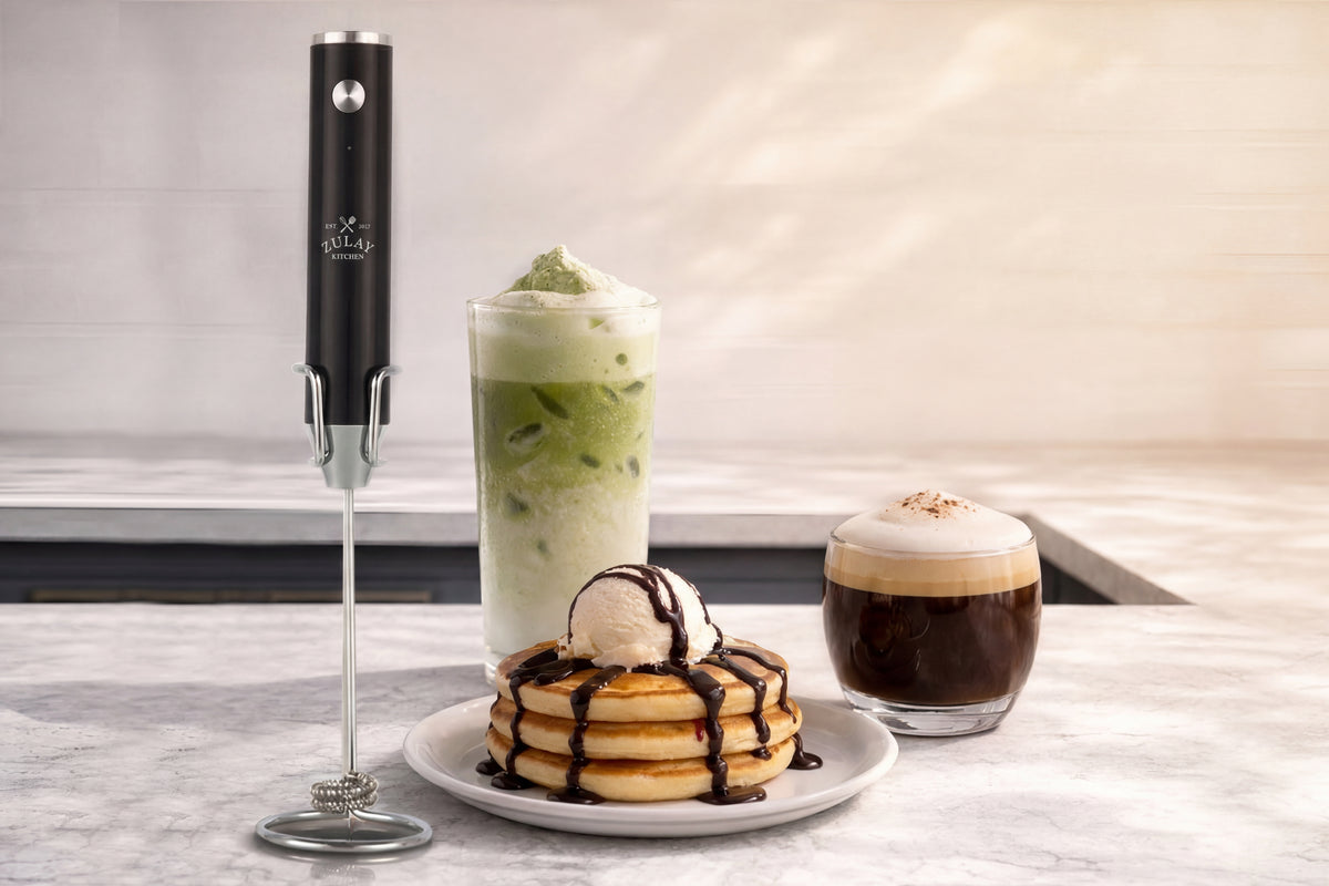 lux milk frother with pancakes, iced coffee, and espresso on a marble surface.