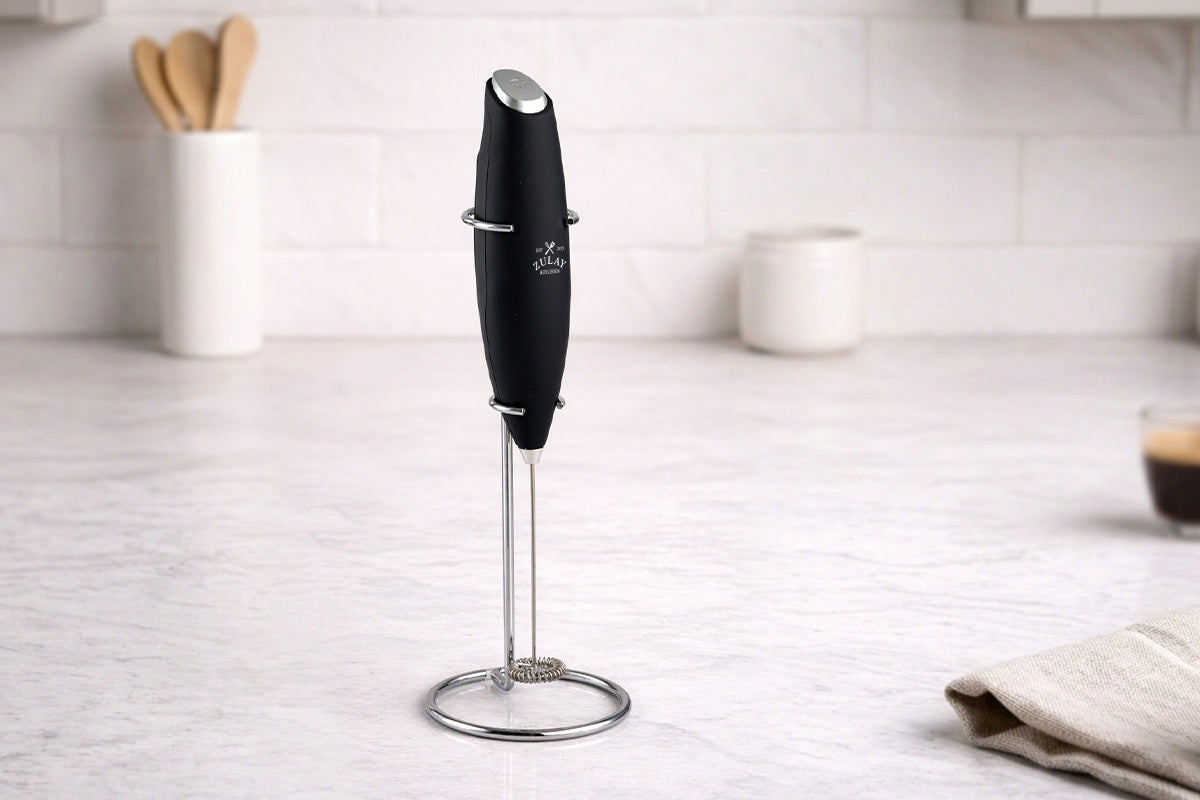 Zulay Kitchen Milk Frother With Stand on a kitchen counter with a blurred background