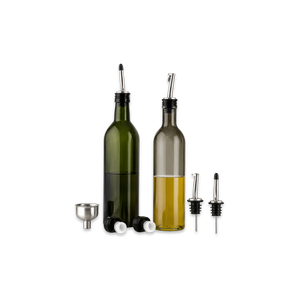 Two bottles of olive oil on a kitchen counter with a salad and ingredients.
