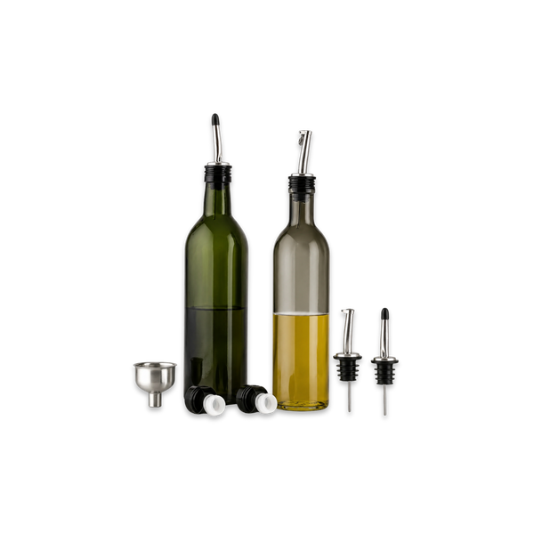 Two bottles of olive oil on a kitchen counter with a salad and ingredients.