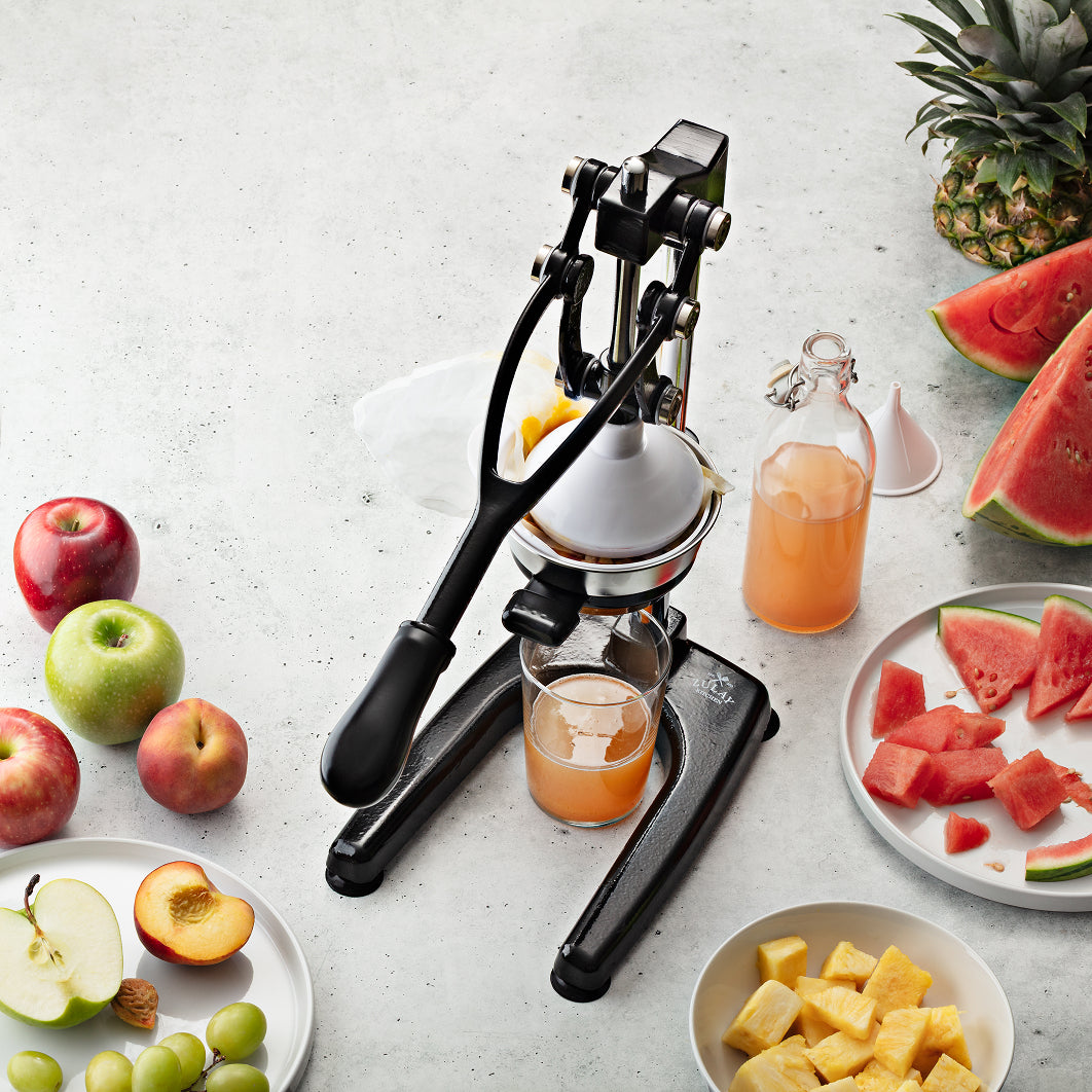 Zulay Kitchen pulperizer juicer with fresh fruits and juice on a light surface
