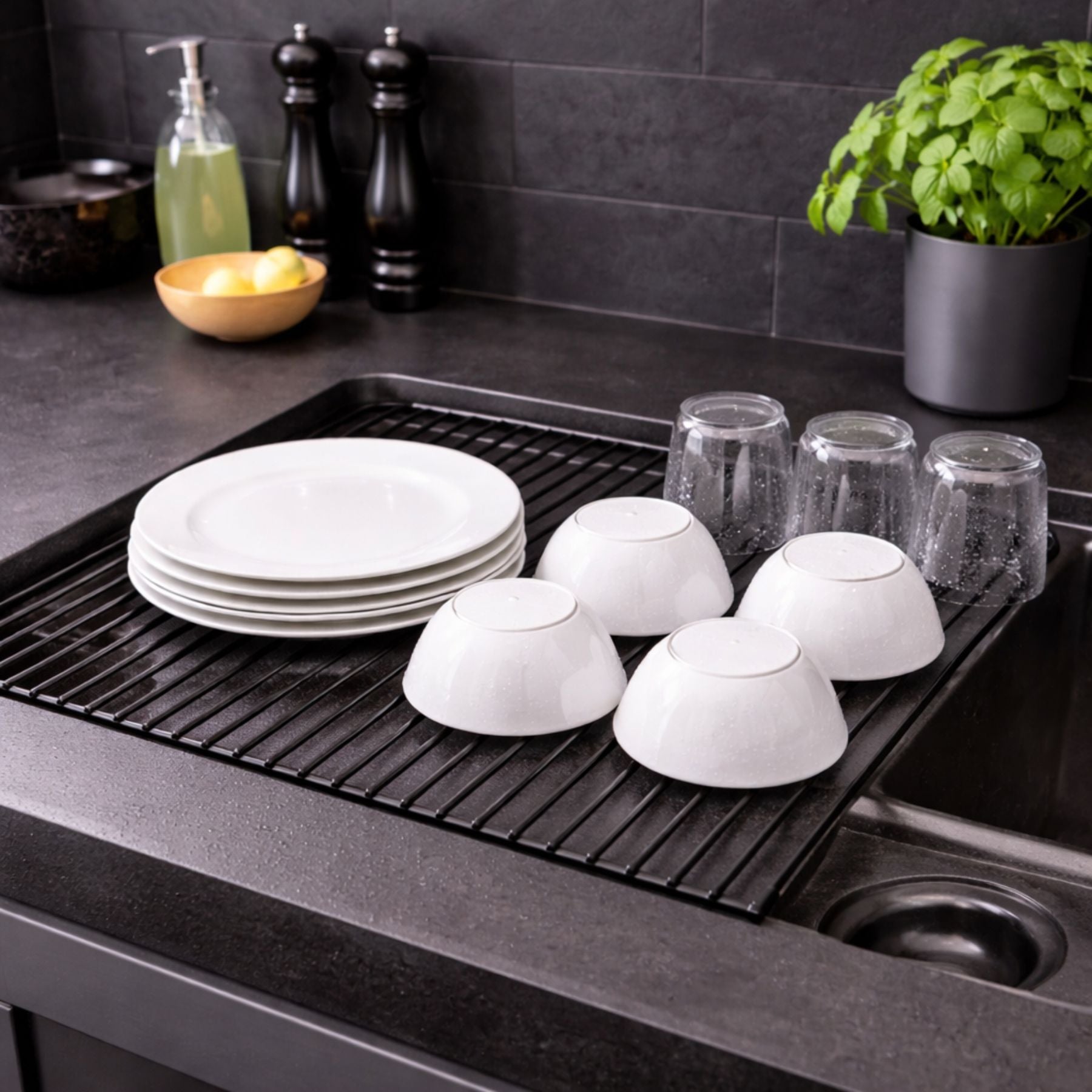 Dish drying rack with white dishes on a kitchen counter.