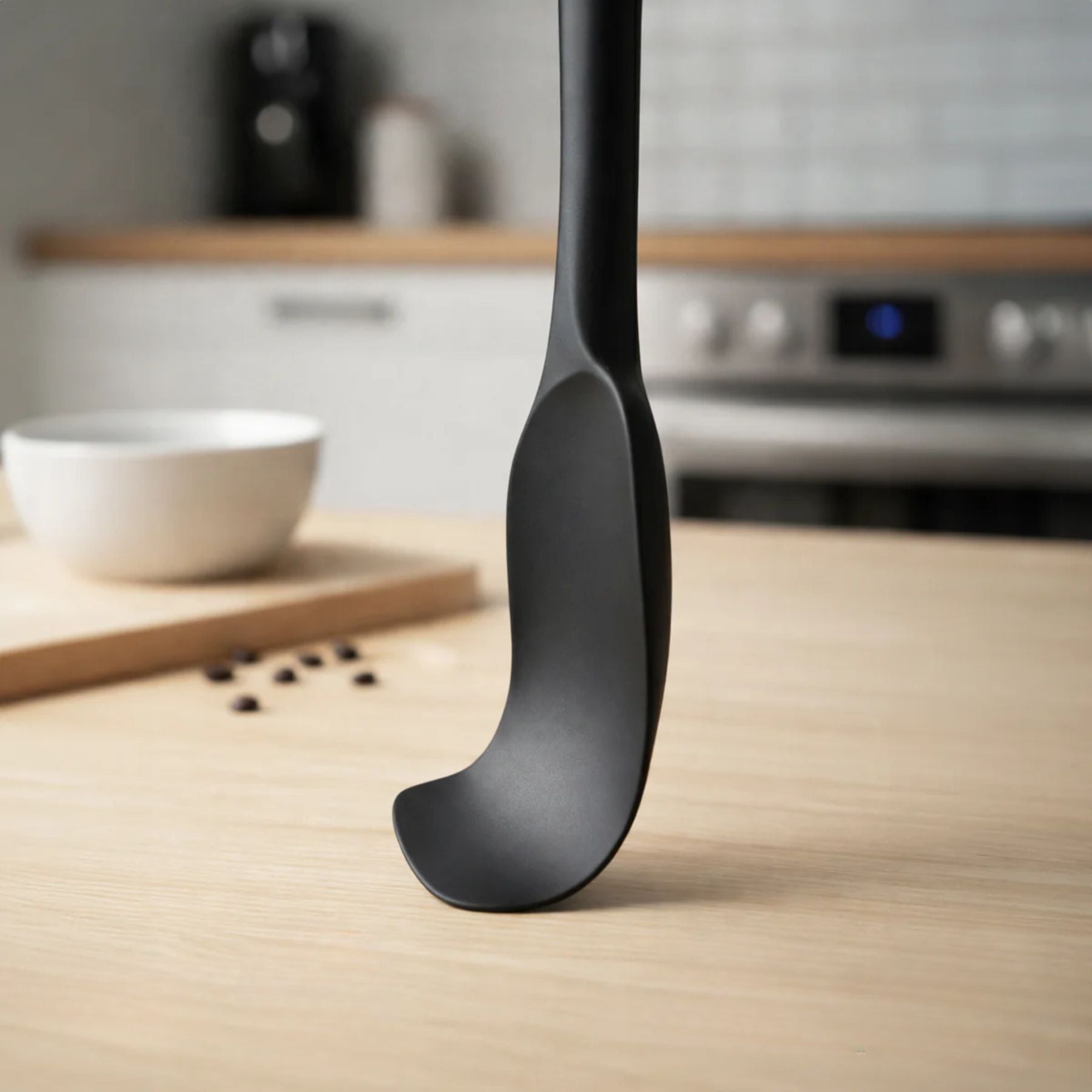 Black Zulay kitchen silicone spatula on a wooden surface with kitchen items in the background