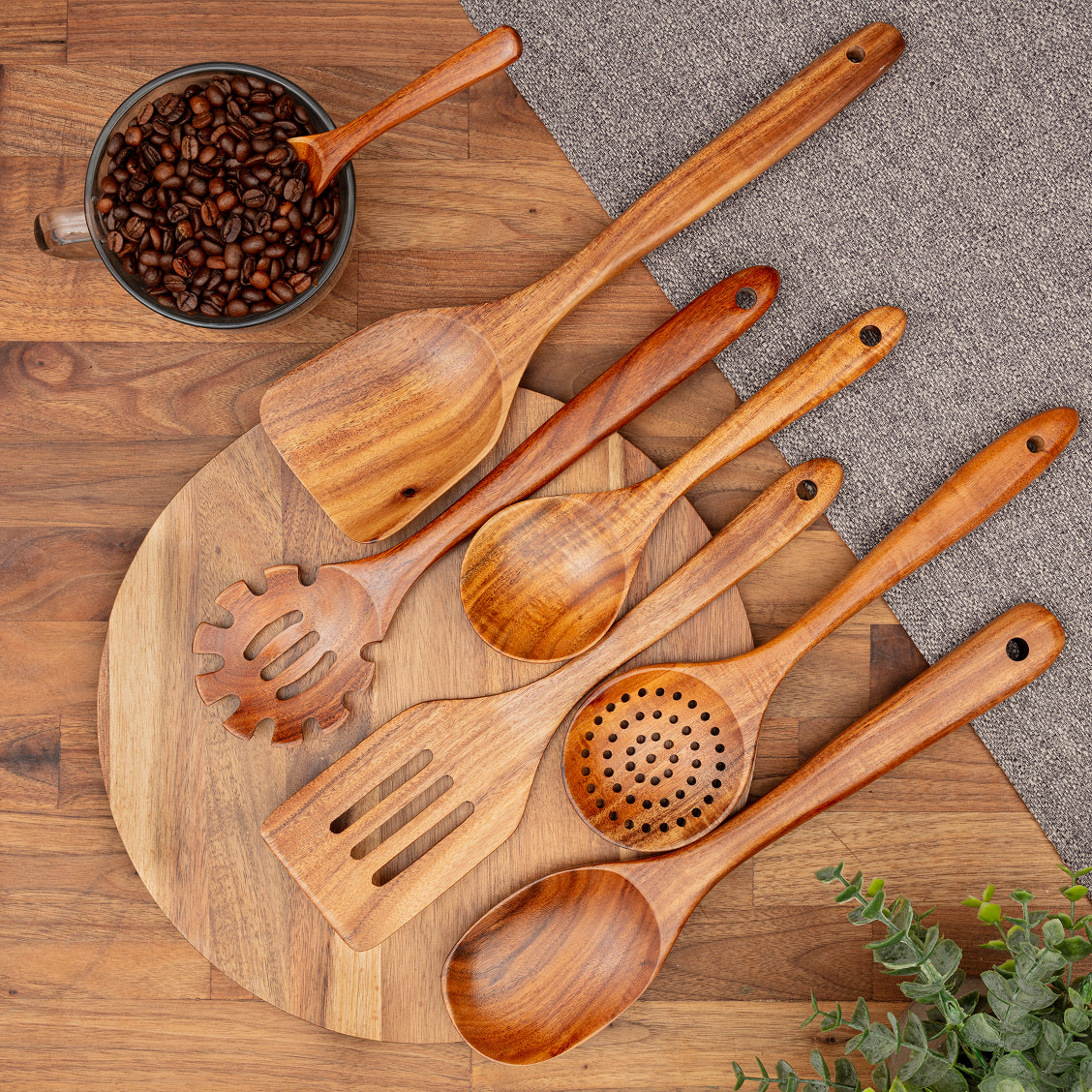 Set of teak wood kitchen utensils on a wooden board with coffee beans.
