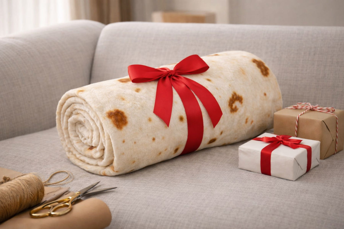 Rolled tortilla blanket with a red ribbon on a couch next to wrapped gifts and scissors.
