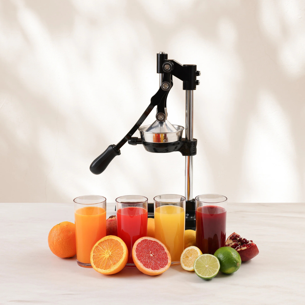 Zulay Kitchen black Cast-iron juicer on a kitchen counter with different kinds of fruits. 