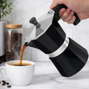 Pouring espresso using a black Zulay Kitchen moka pot into a cup.