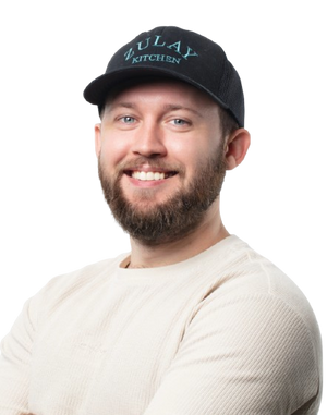 Jeremy wearing a black cap with 'ULAY KITCHEN' logo on a white background