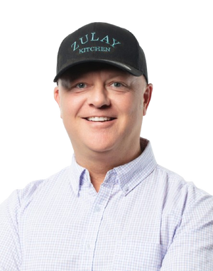 Stephen wearing a black cap with 'Zulay Kitchen' logo on a white background
